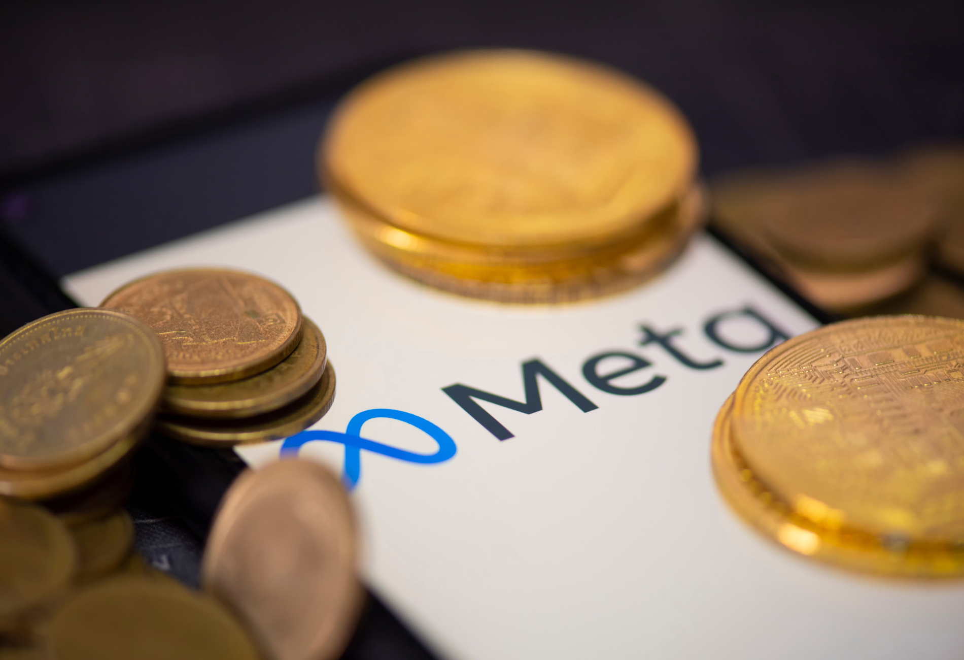 coins atop a phone screen displaying Meta's logo