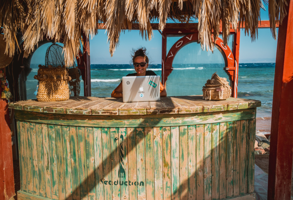 woman smiling while working on her laptop in a beach bar