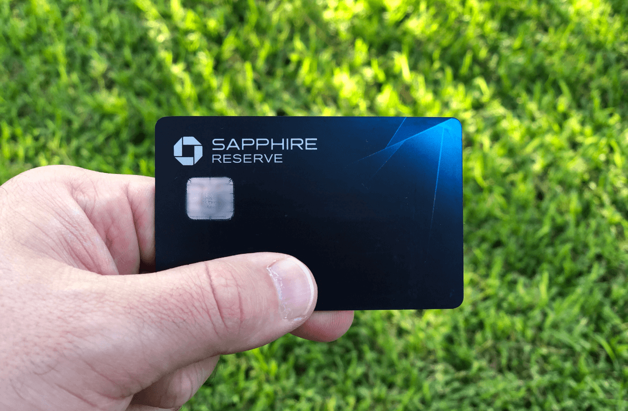 man holding chase sapphire reserve card with grass in background