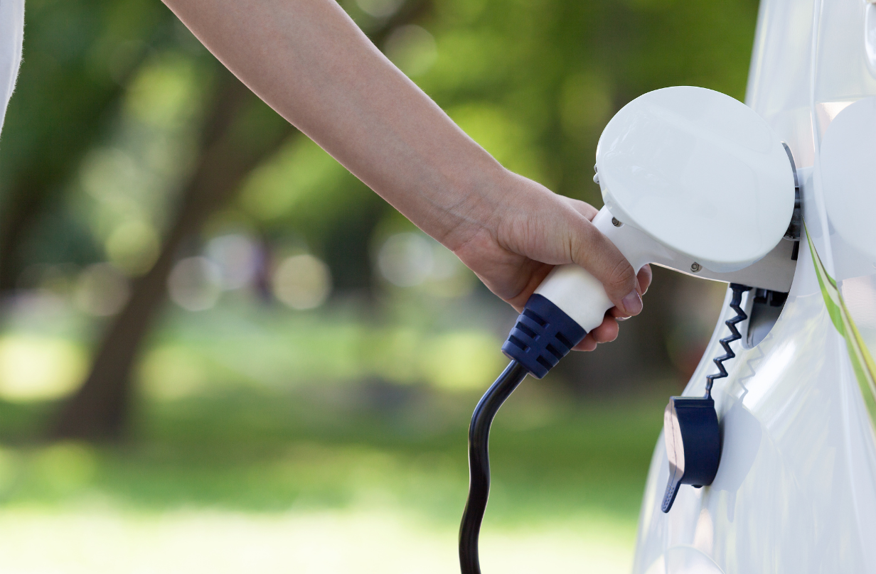 person putting electric car charger into car