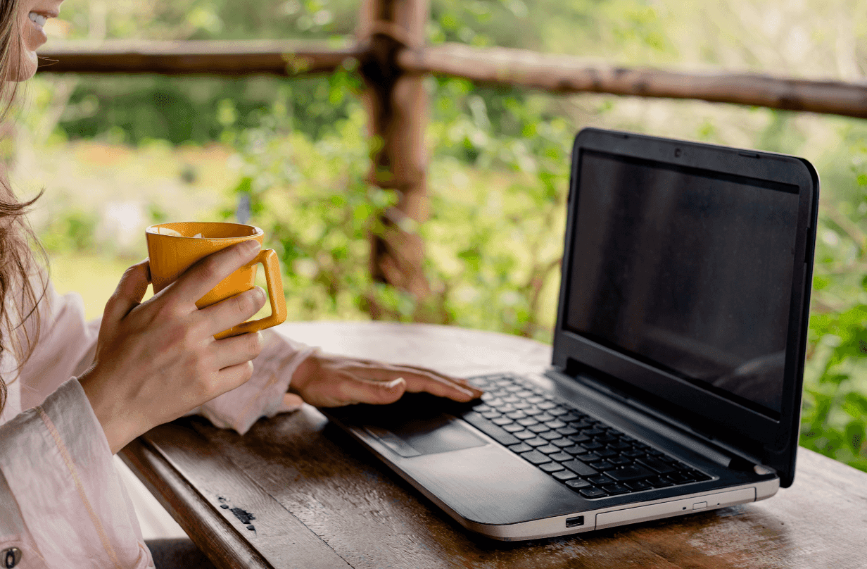 person working on laptop holding coffee