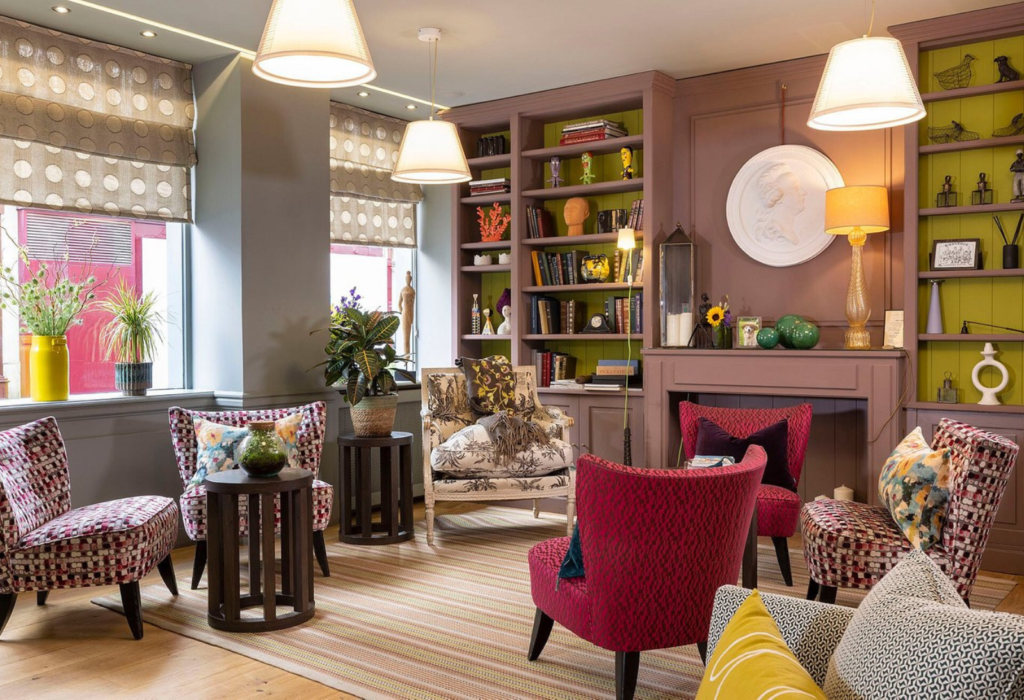 lobby in hotel with red velvet chairs and a bookcase