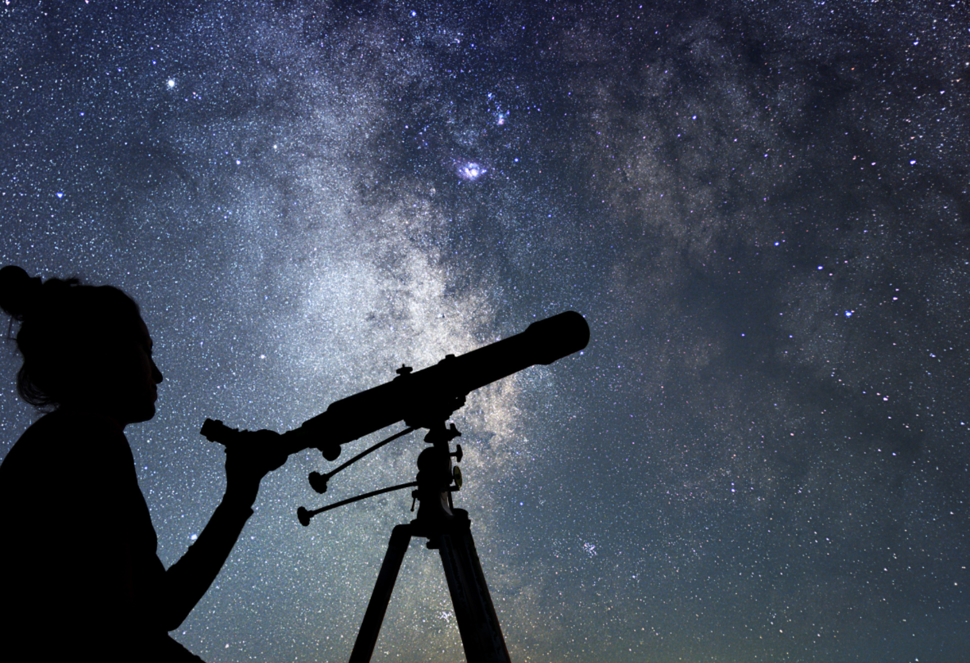 person with telescope looking up to a starry night