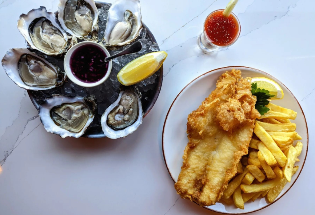 fish and chips on one plate and fresh raw oyster on another