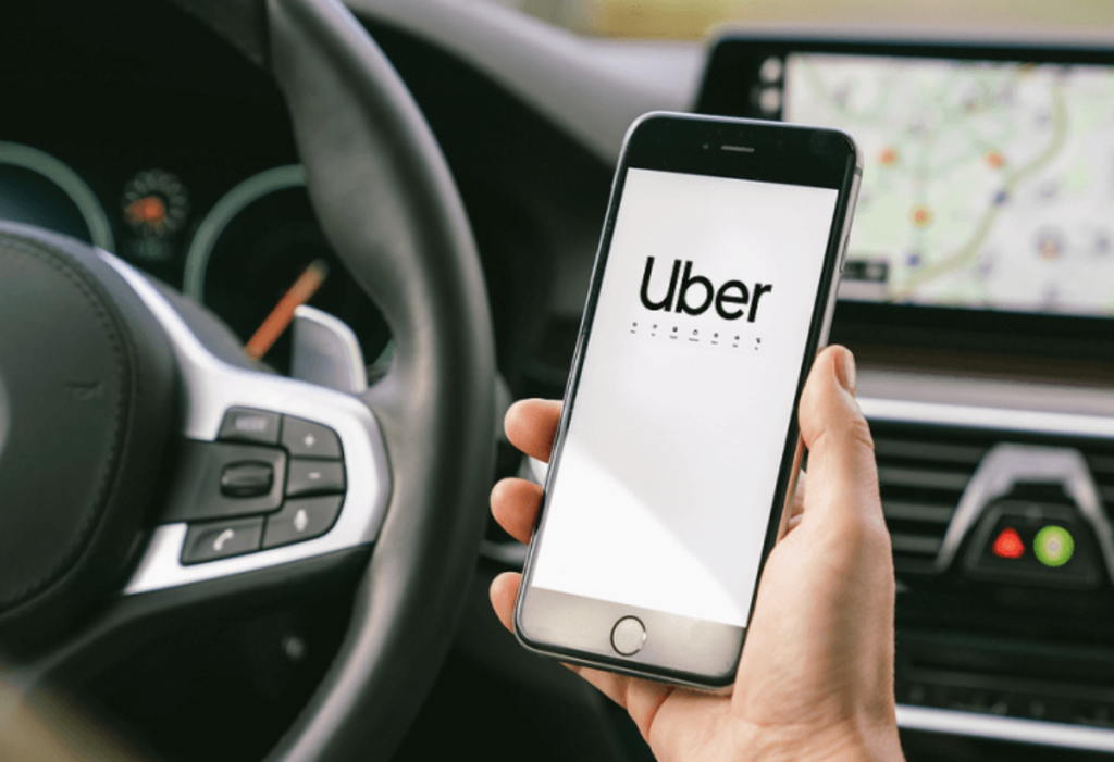 person holding phone with Uber logo on it as they drive car