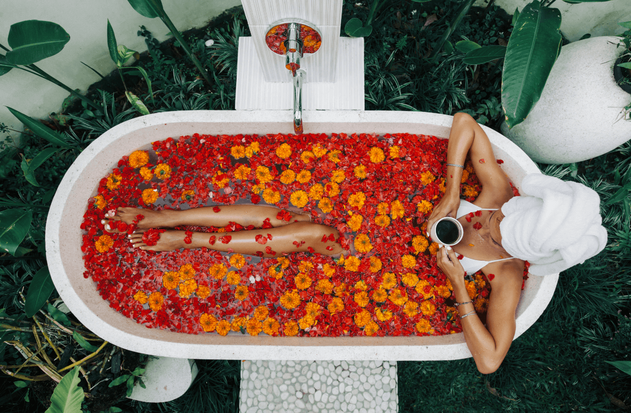 person laying in bathtub with flowers