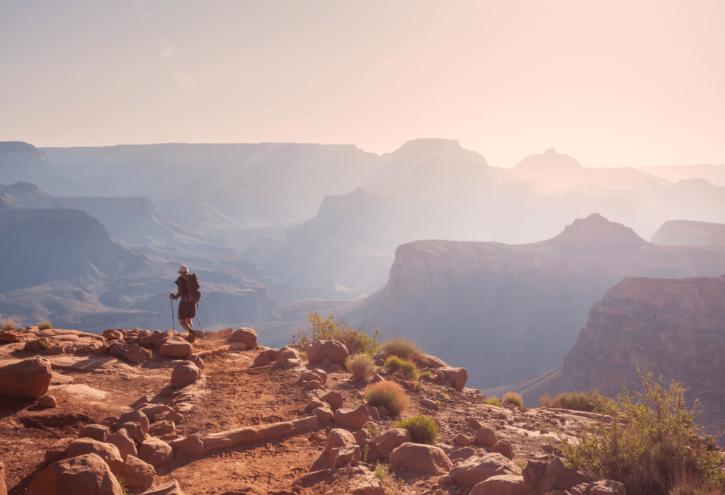 hiker walking near the rim of the grand canyon