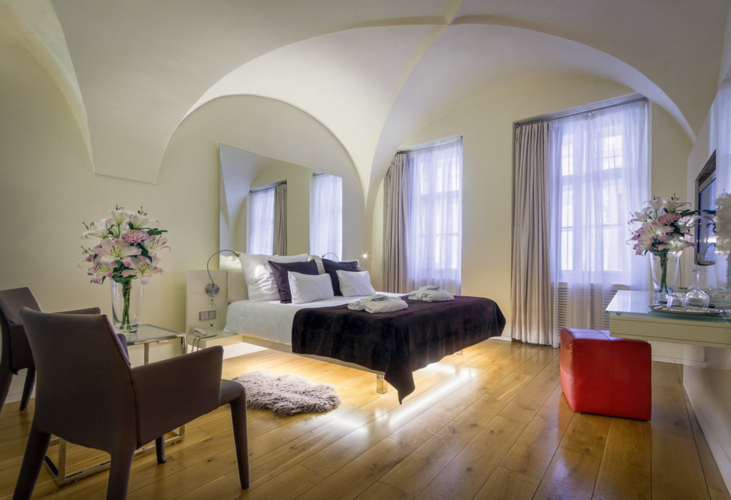 hotel bedroom with curved white ceilings, wooden floors, and a bed