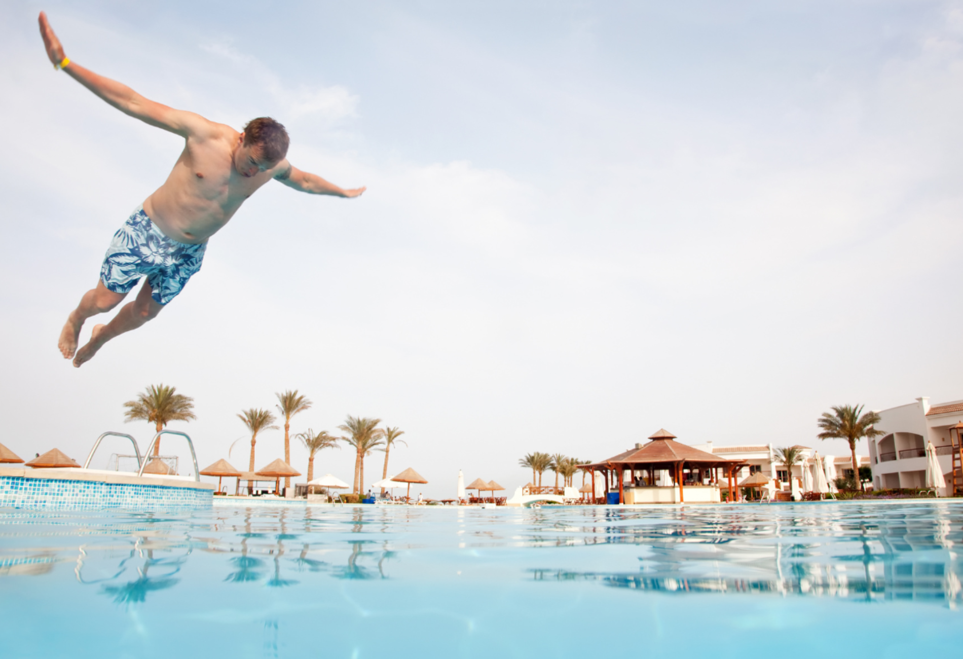 man doing a belly flop into a hotel pool