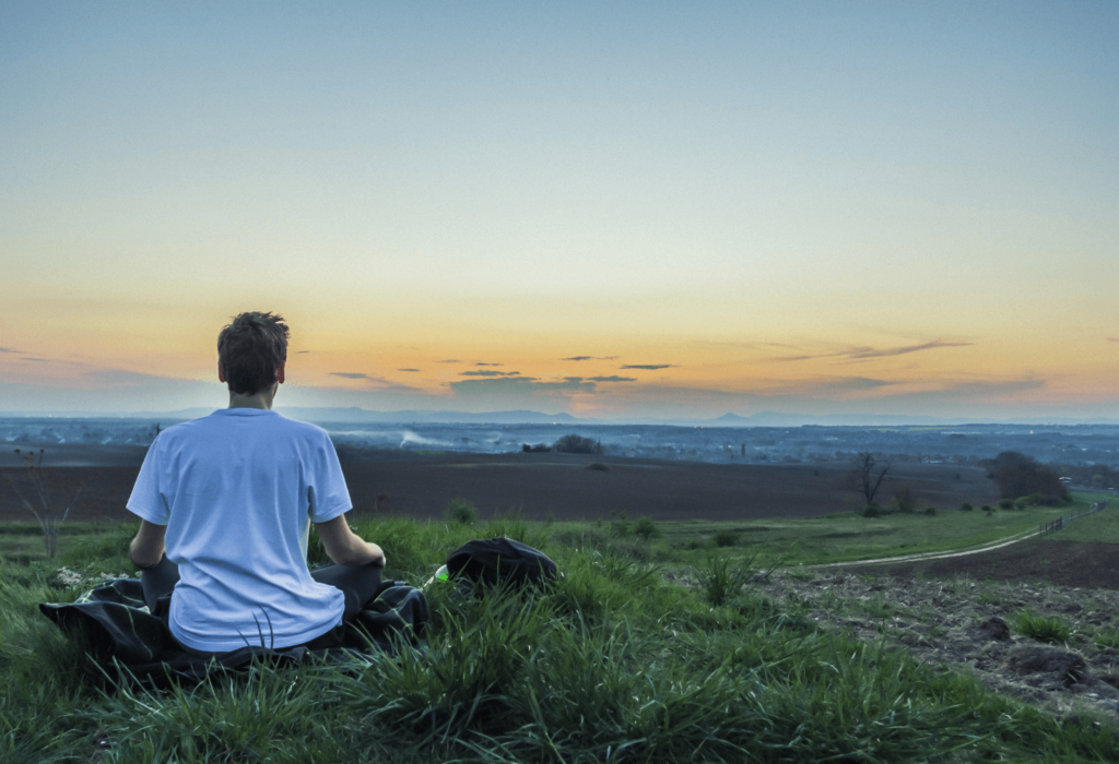 man meditating in a field