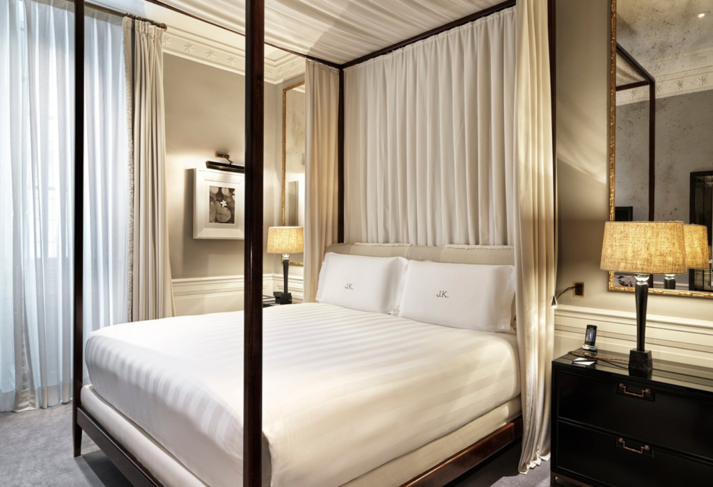 four-post bed with white linens in a hotel room