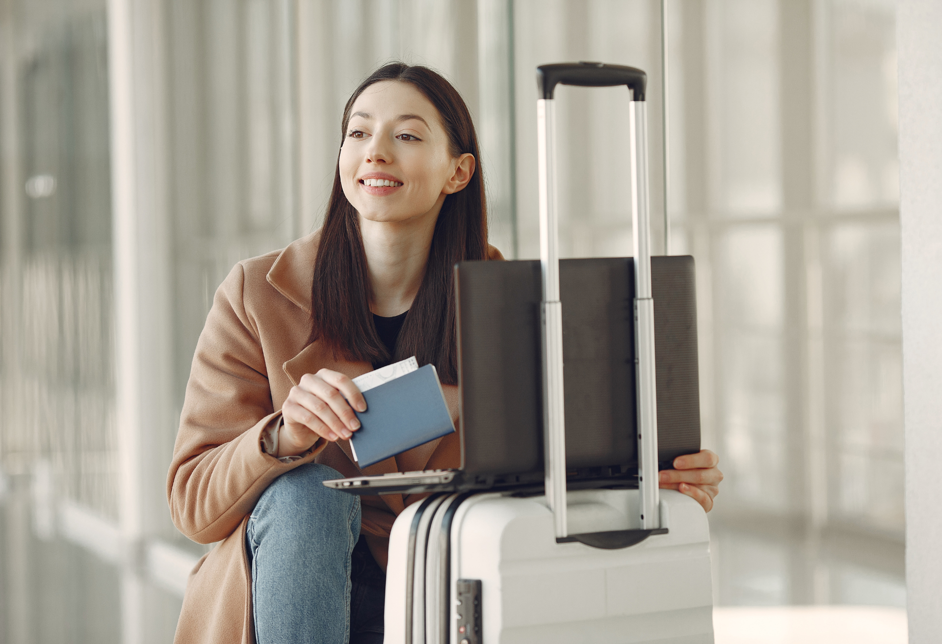 woman on laptop with luggage at airport