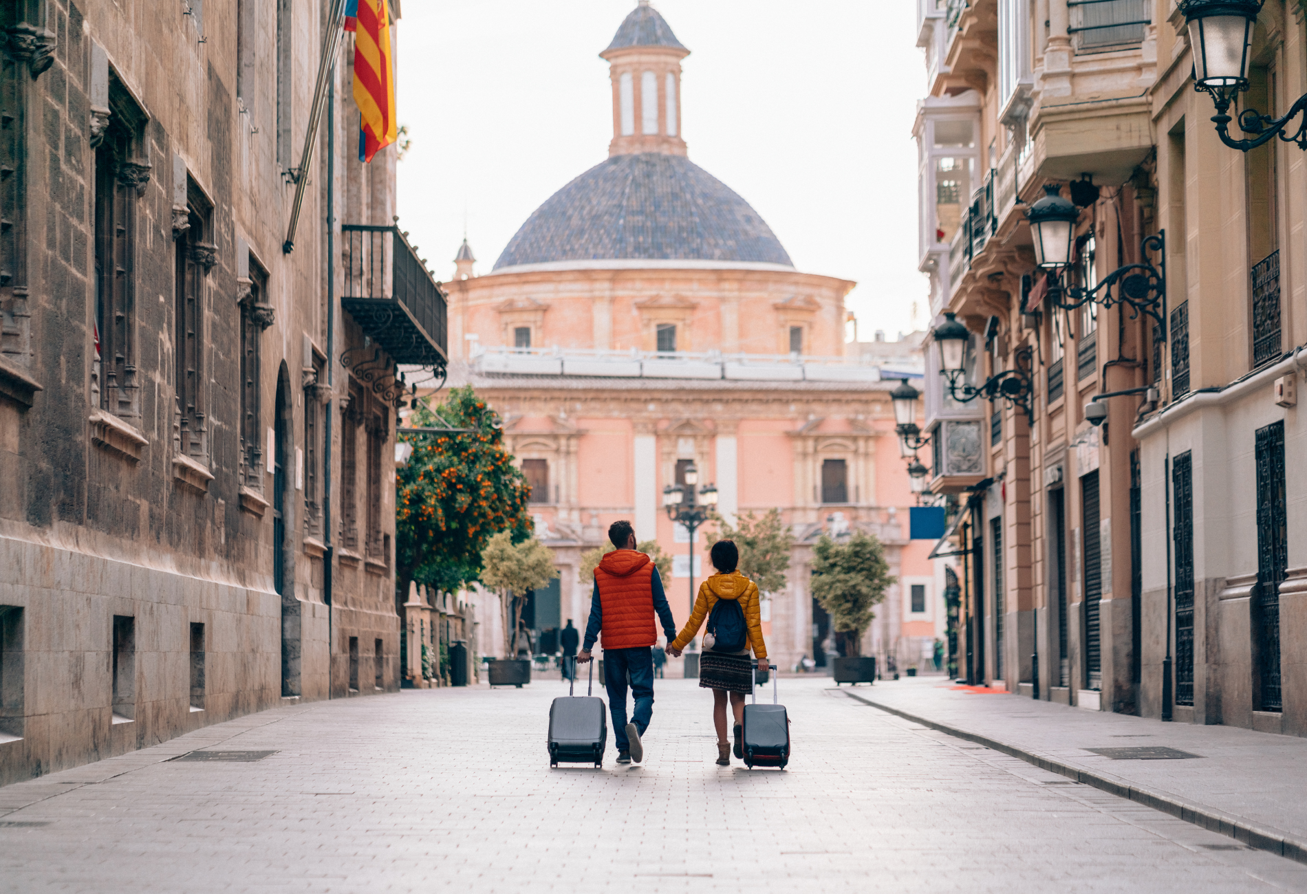 couple with suitcases walking down the street