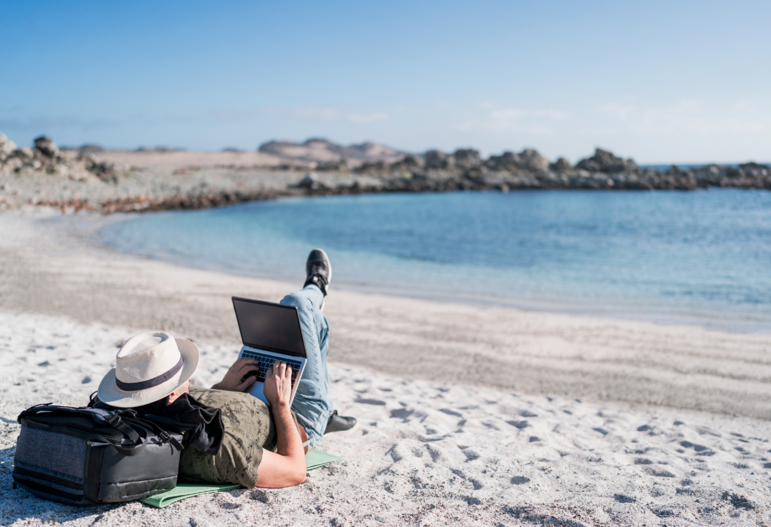 person on laptop laying on the beach