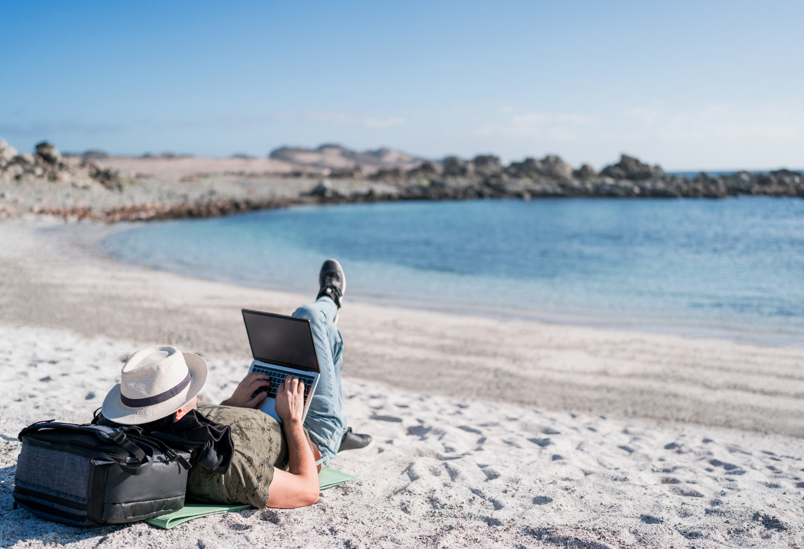 person on laptop laying on the beach