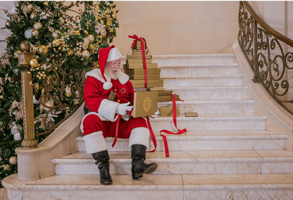 santa sits on the stairs at the plaza hotel new york