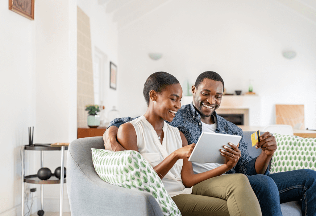 couple sitting on couch with credit card for article on the American Express Gold card