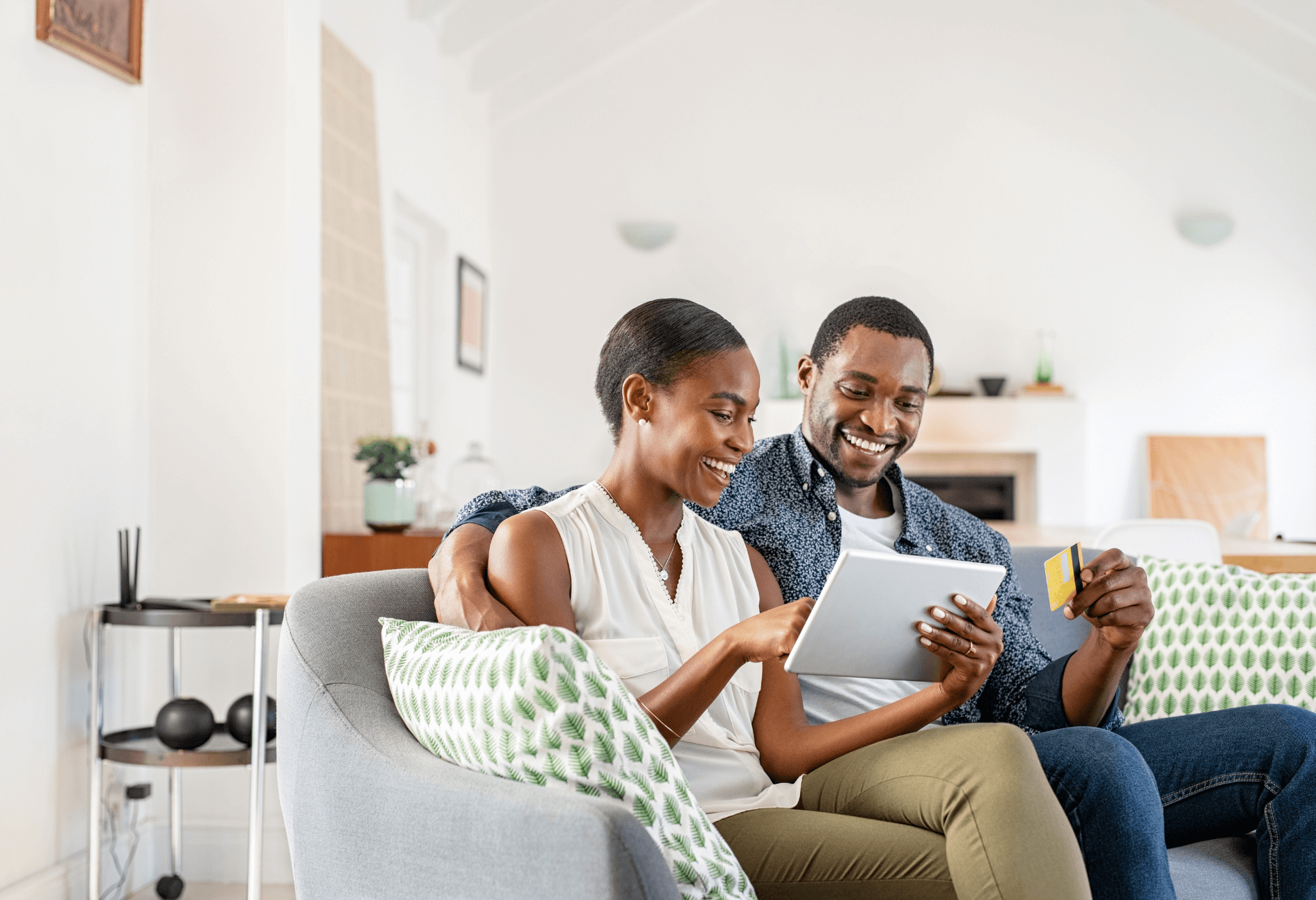 couple sitting on couch with credit card for article on the American Express Gold card