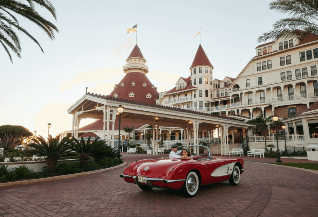 A classic red sports park drives by the lobby of the Hotel de Coronado