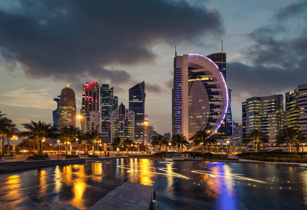 The skyline in Qatar's capital city of DOha at sunset for article on how to book qsuite flights to Qatar using points and miles