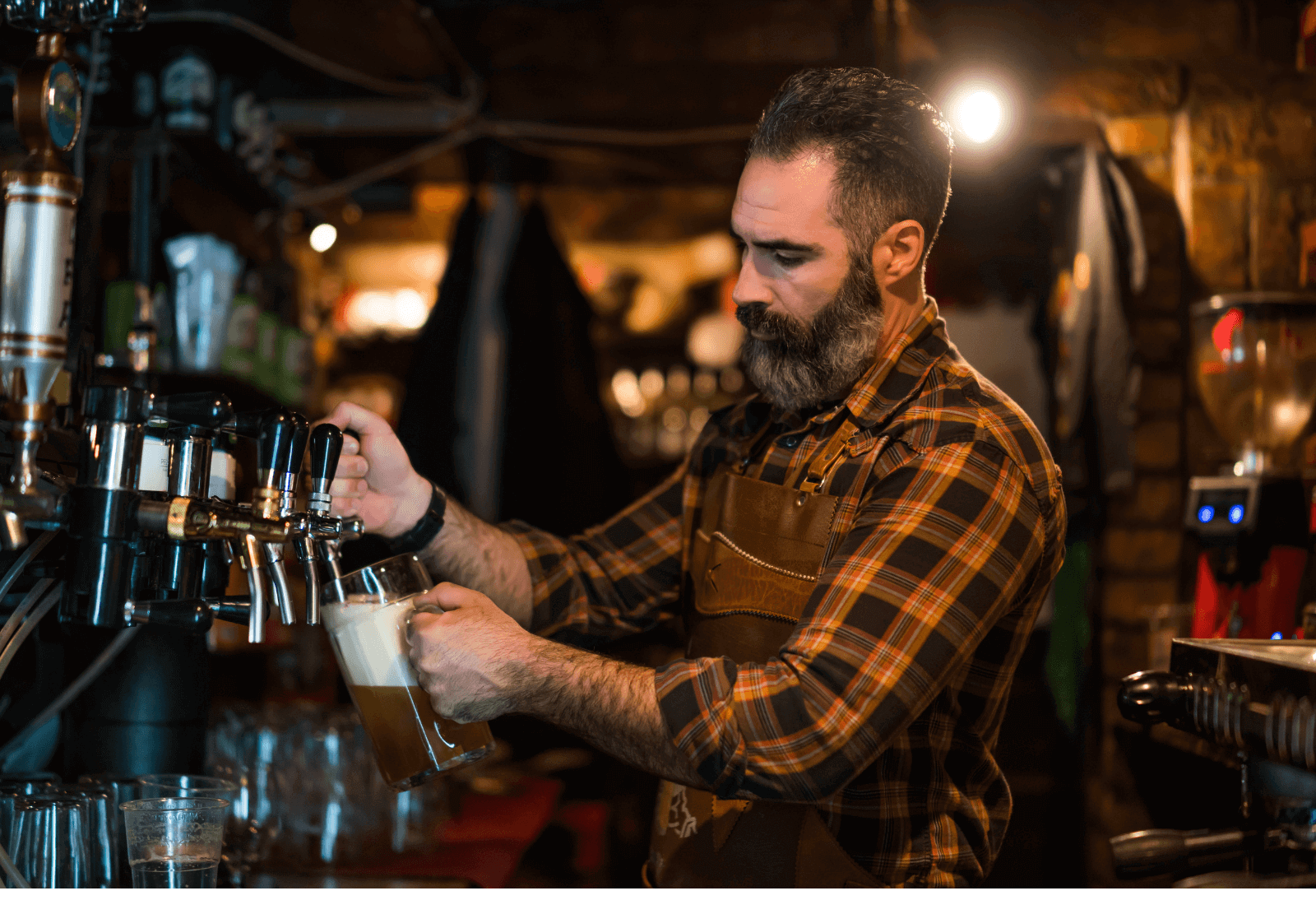 A barman in a brewery pouring a pint of lager