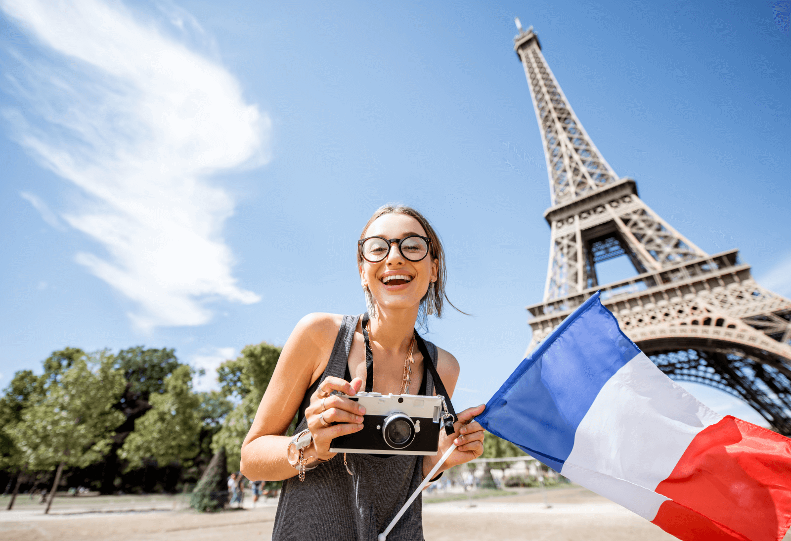 Girl standing next to the Eiffel Tower in Paris with a French flag